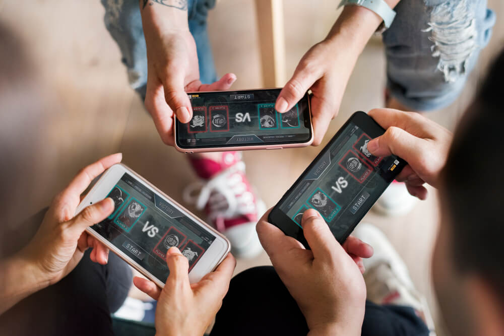 Group of diverse friends playing game on mobile phone. Best Multiplayer Games for Android.