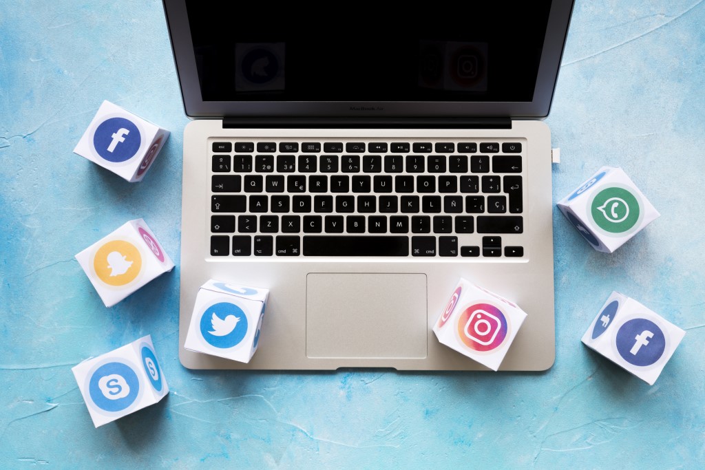 Social media icon blocks on laptop over the blue background, Social media in the business world.
