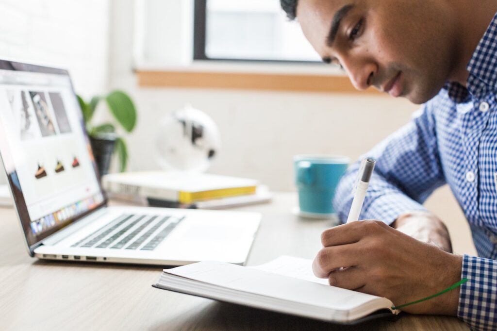 Man using laptop computer and writing