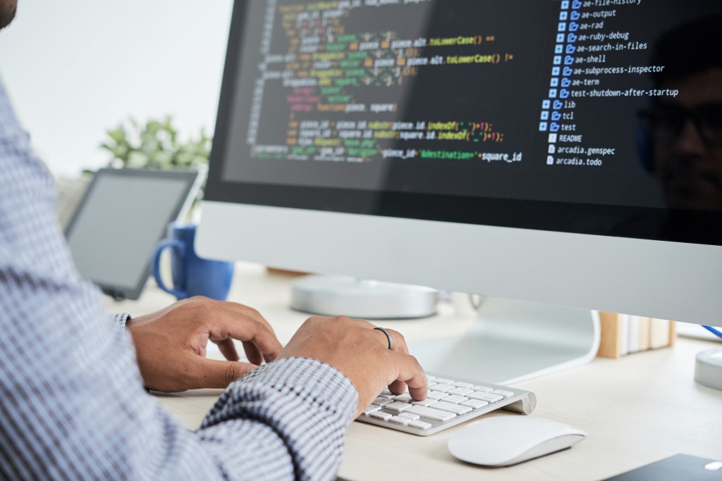 Male Software Developer Coding Software on a iMac Desktop Computer, Software Development.