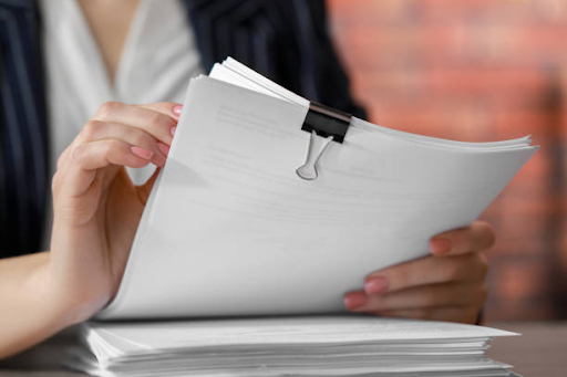 Document verification process. Woman stacking documents at table in office.