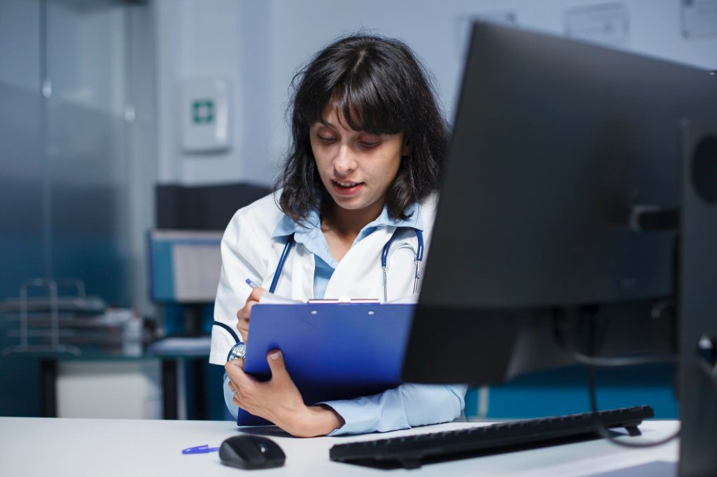 Young Medical Practitioner/Doctor Writing on Her Clipboard