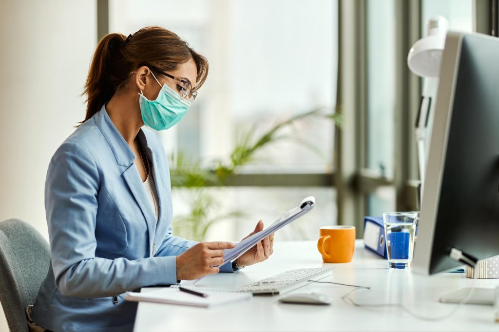 Young Woman Wearing Protective Face Mask While Going Through Medical Documentation and Reports